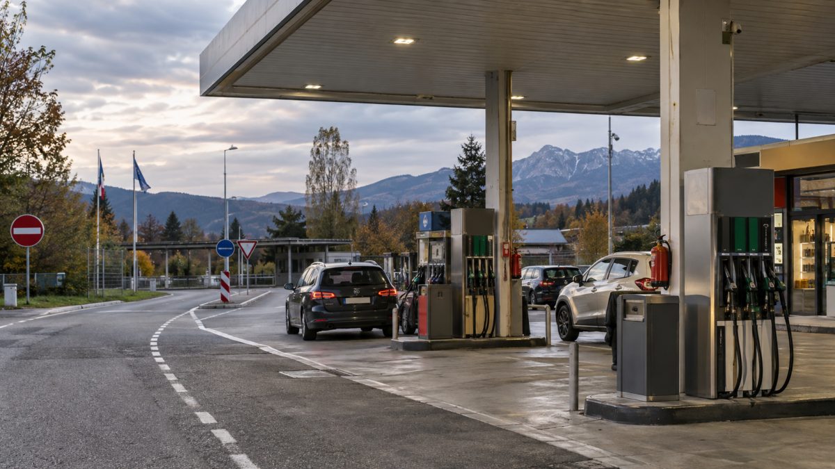 European petrol station with several fuel pumps and cars in late-day light
