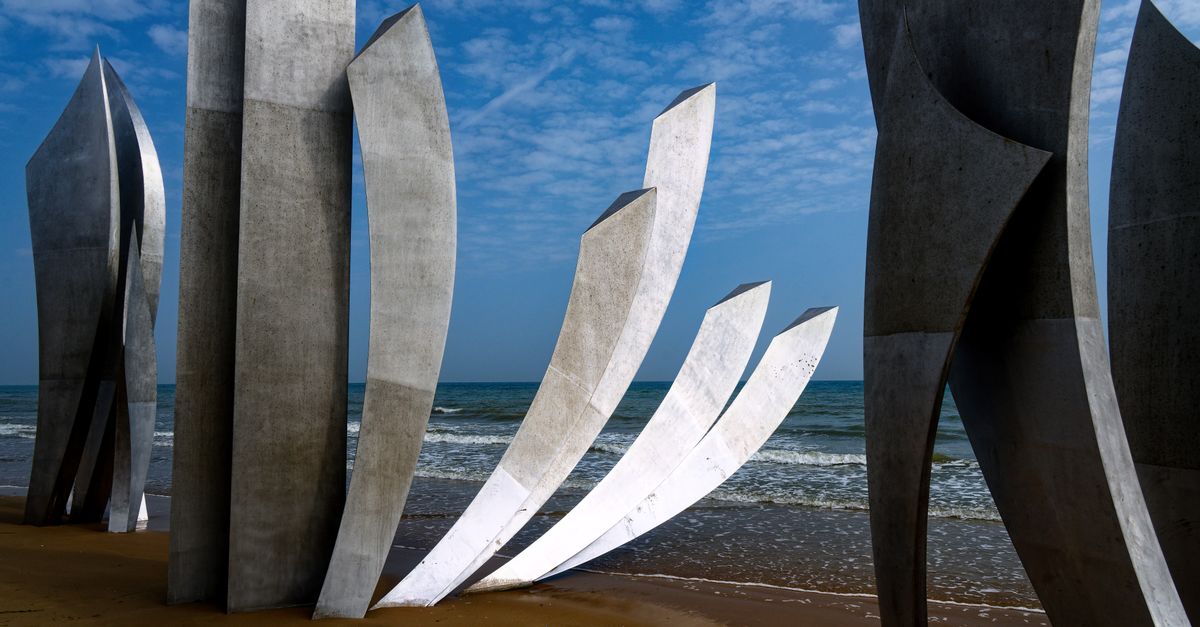 D-Day 2026追悼行事で、上陸作戦記念碑と旗があるノルマンディーの海岸