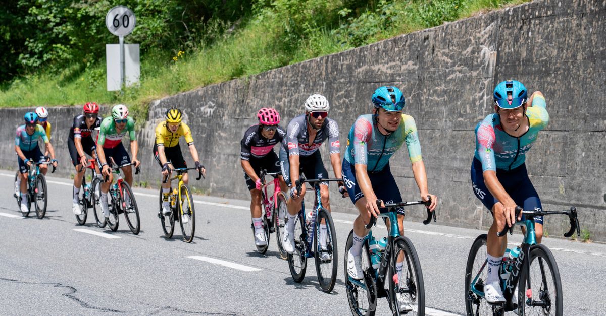Gruppo di ciclisti professionisti in gara su una strada di montagna tortuosa durante una grande corsa ciclistica estiva
