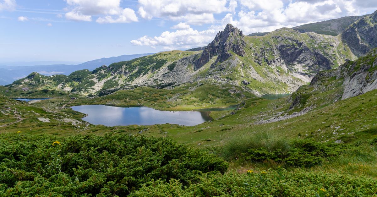 Lago de montaña rodeado de cumbres verdes, destino fresco para escapar de la ola de calor del verano de 2026