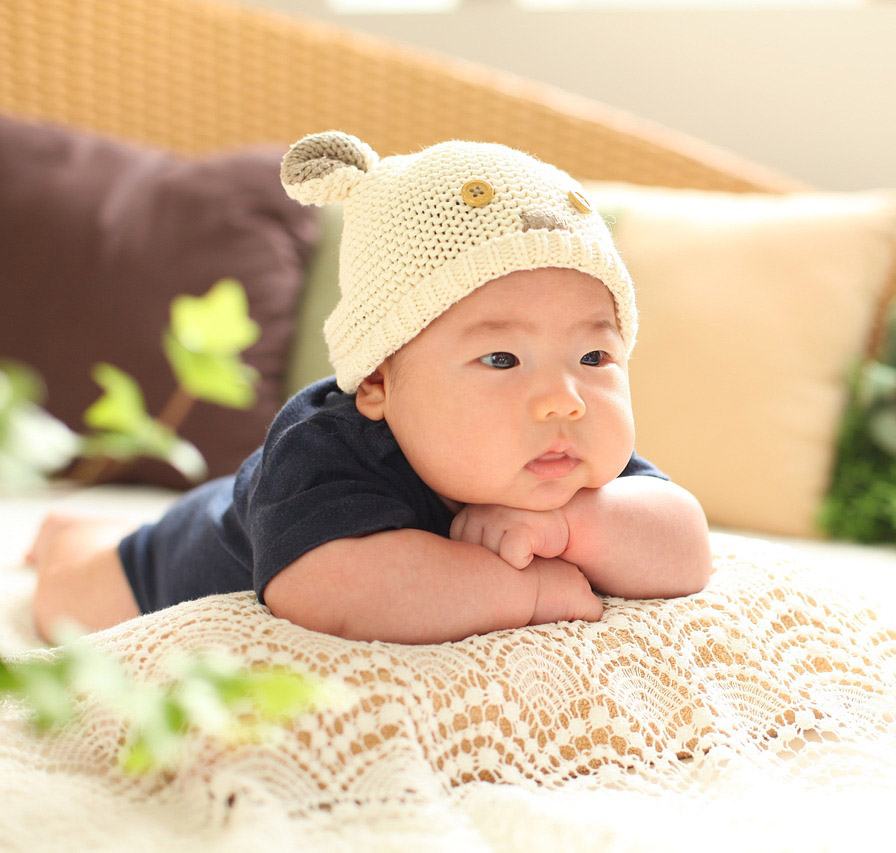 3 Monate altes Baby auf einer Spielmatte lachend und nach buntem Spielzeug greifend